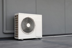 Condensing unit of air conditioning systems. Condensing unit installed on the gray wall.