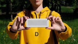 Wireless speaker in girl's hand with nature on background