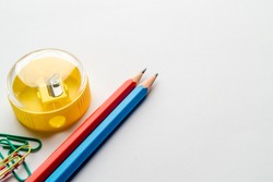 Office supplies - pencils, pencil sharpener, paper clips on a white background