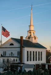 A Unitarian Church and the American flag in golden hour light. Massachusetts, New England.