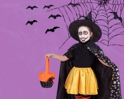 Halloween kids. A little girl in a costume and scary makeup with a candy basket. Trick or treat