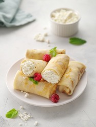 Crepes with cottage cheese, strawberry and mint. Thin pancakes with fillings. Pancake week or Shrovetide. Pancakes flapjack thin cake curd filling crepe cottage cheese.