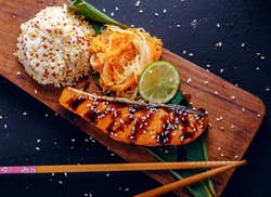 Teriyaki salmon with rice on a wooden platter. Top view.