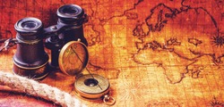 Old vintage retro compass and binoculars on ancient world map. Travel geography navigation concept background. Vintage still life