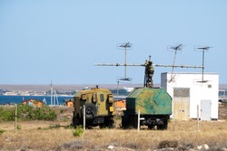 Mobile military radar station on wheels for detecting aerodynamic and ballistic objects. The military facility is located in the steppe on the seashore.