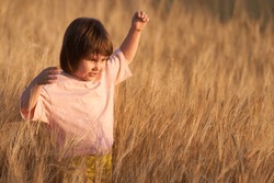 An enthusiastic child in a field of rye in the soft light of the setting sun. Copy space.                               