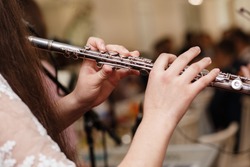 Flutist, young girl playing the flute, hands, fingers on keys closeup, children playing transverse side blow flute, detail shot, classical music, wind instrument performance player up close abstract