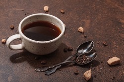 Cup of coffee in dark tones. Morning good mood, breakfast concept. Brown sugar, cutlery, hard light, dark shadow, stone concrete background, copy space