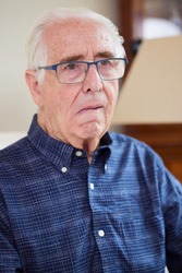 Portrait Of Senior Man At Home Suffering From Stroke Showing Dropped Side Of Face