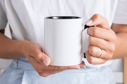 Two tone black and white mug mockup for presentation sublimation designs. Stock photos of white coffee mug in the female hands  for designers