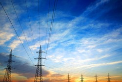Pylons and power lines at sunset with vibrant sky,clouds and sun