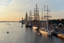 The world largest tall ships participating in race regatta are berthed by a quay of passenger terminal at the Daugava river in the port of Riga, Latvia. Masts decorated with marine flags. Sails down. 
