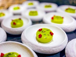 Mousse green cakes made from delicate cream mousse.garnished with pistachios and dried raspberries.small one-bite cakes are called petit fours.at catering event on some festive event,party or wedding