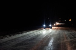 Mazowieckie, Poland - December 5, 2021: Night photo of road traffic in winter. Car lights reflecting off an icy, slippery road.