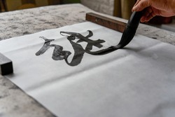An old Chinese calligrapher is creating and writing calligraphy works.
Translation: carry on the past and open up the future.