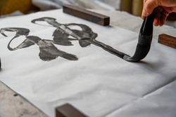 An old Chinese calligrapher is writing brush characters, creating Chinese calligraphy works.
Translation: Spring comes, the god of wind arrives.