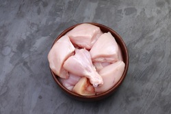 Raw chicken tender curry cut without skin arranged on wooden bowl on stone textured or graphite coloured background,isolated