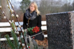 Woman in cemetery sits at a grave in deep sadness about death and loss