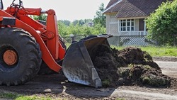Heavy wheeled bulldozer removes a ground from road side. European country roads repair, road building machines equipment