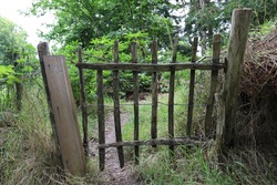 A wooden gate made of old wood and a mesh fence.