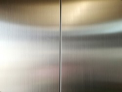 Stainless steel large sheet  With light hitting the surface  For background,Inside passenger elevator,Reflection of light on a shiny metal texture,stainless steel background.