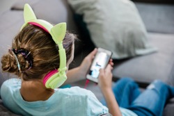 Tween Teen girl listening to music on the couch with cat headphones