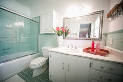 Small outdated tile bathroom with a clear glass door and a white cabinet sink vanity and mirror