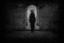 A spooky ghost, walking towards the camera, framed by the archway of an old building. With a grunge, vintage, blurred edit.