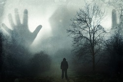 A man looking up at a huge ghostly hooded figure appearing out the mist. On a moody winters day in the countryside. With a grunge, vintage edit.