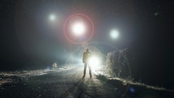 UFO concept. Glowing orbs, floating above a misty road at night. With a silhouetted figure looking at the lights.               