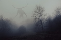 A fantasy concept of a horned god like monster. Looking across a forest on a spooky foggy, winters day. 
