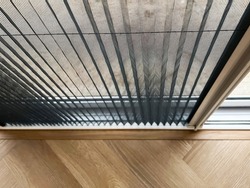 Selective focus mosquito net wire screen on door near wooden floor.