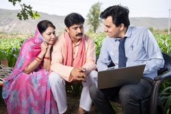 Happy rural indian farmer family with agronomist or banker use laptop. Man officer showing policy on computer screen, Financial support or farming crop loan,  husband wife with government scheme agent