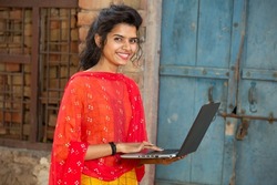 Portrait of young indian woman using laptop. Smiling female wearing traditional cloths holding learning computer. skill india concept.