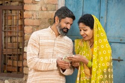 Happy rural couple holding indian rupees notes, Smiling Beard man give money to his wife.