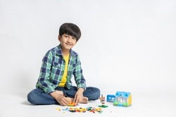 Portrait of happy indian child boy playing colorful blocks toy, isolated on white studio background. Educational toys for elementary and kindergarten kid.