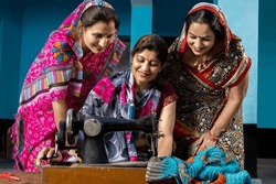 Portrait happy traditional indian woman wearing sari teaching other females how tu use sewing machine. Skill india Concept.