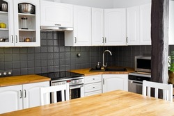 Modern white color home kitchen corner with solid natural color oak wood countertop and  various appliances.