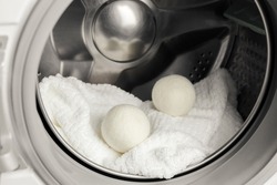 Using wool dryer balls for more soft clothes while tumble drying in washing machine concept. Discharge static electricity and shorten drying time, save energy.