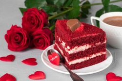 Piece of Red Velvet cake, cup of coffee and roses for Valentines Day or birthday on gray background