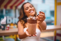Young afro woman holding a milkshake in her hand. Woman with a milkshake