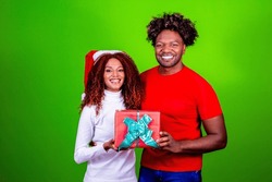 brazilian couple, dressed for christmas, santa claus, mummy claus. exchanging gifts. approved, black woman and black man.