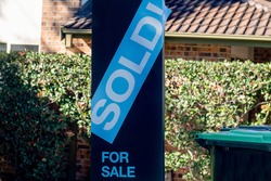 For sale sign near the residential building house with 'SOLD' sold sticker on it. Auction clearance rate