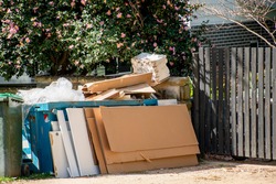 Household miscellaneous rubbish items piled outside the residential building on kerbside for council waste collection.