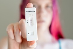 Teenage girl holding Covid-19 rapid antigen test cassette with positive result of rapid diagnostic test. Selective focus