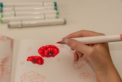 Hand drawing a red poppy wreath sketch in a sketchbook with alcohol based sketch drawing markers. Remembrance Day and Anzac day.