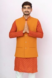 A portrait of a indian man in a traditional wear in welcome gesture pose - Namaste.