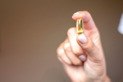 Woman holding fish oil capsule. Hand holding capsule of Omega 3. Close up. Copy space
