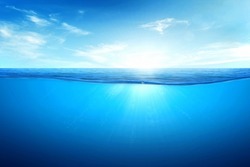 BLUE UNDER WATER waves and bubbles. Beautiful white clouds on blue sky over calm sea with sunlight reflection, Tranquil sea harmony of calm water surface. Sunny sky and calm blue ocean.
