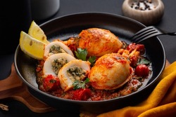 Dish with Sepia, calamari or Cuttlefish stuffed with swiss chard, bread crumbs and parmesan cheese and cooked in tomato sauce. Black background.